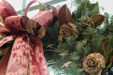 Pulang makintab na laso at pine cone sa wreath