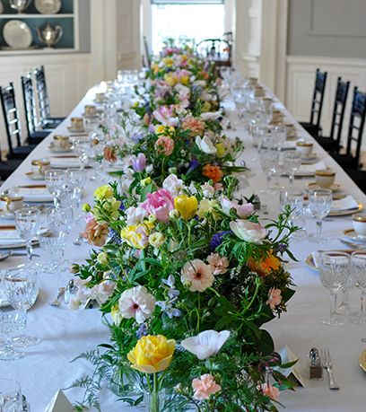 Naka-set ang dining table ng Executive Mansion na may puting table cloth, state china at mga bulaklak.