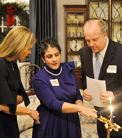 First Lady Suzanne Youngkin, isang babae at isang lalaki na nakasuot ng yarmulke stand sa harap ng isang menorah.