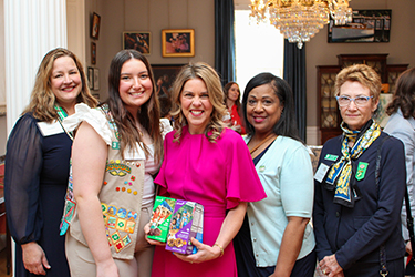 Nagpose ang First Lady na may hawak na Girl Scout cookies kasama ang isang grupo ng mga babae at isang Girl Scout sa loob ng Mansion.